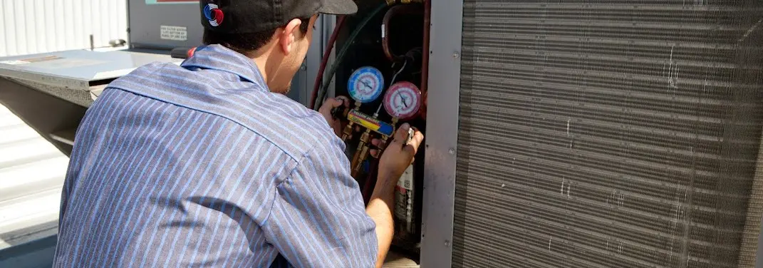 HVAC technician servicing a condenser unit in Bloomer
